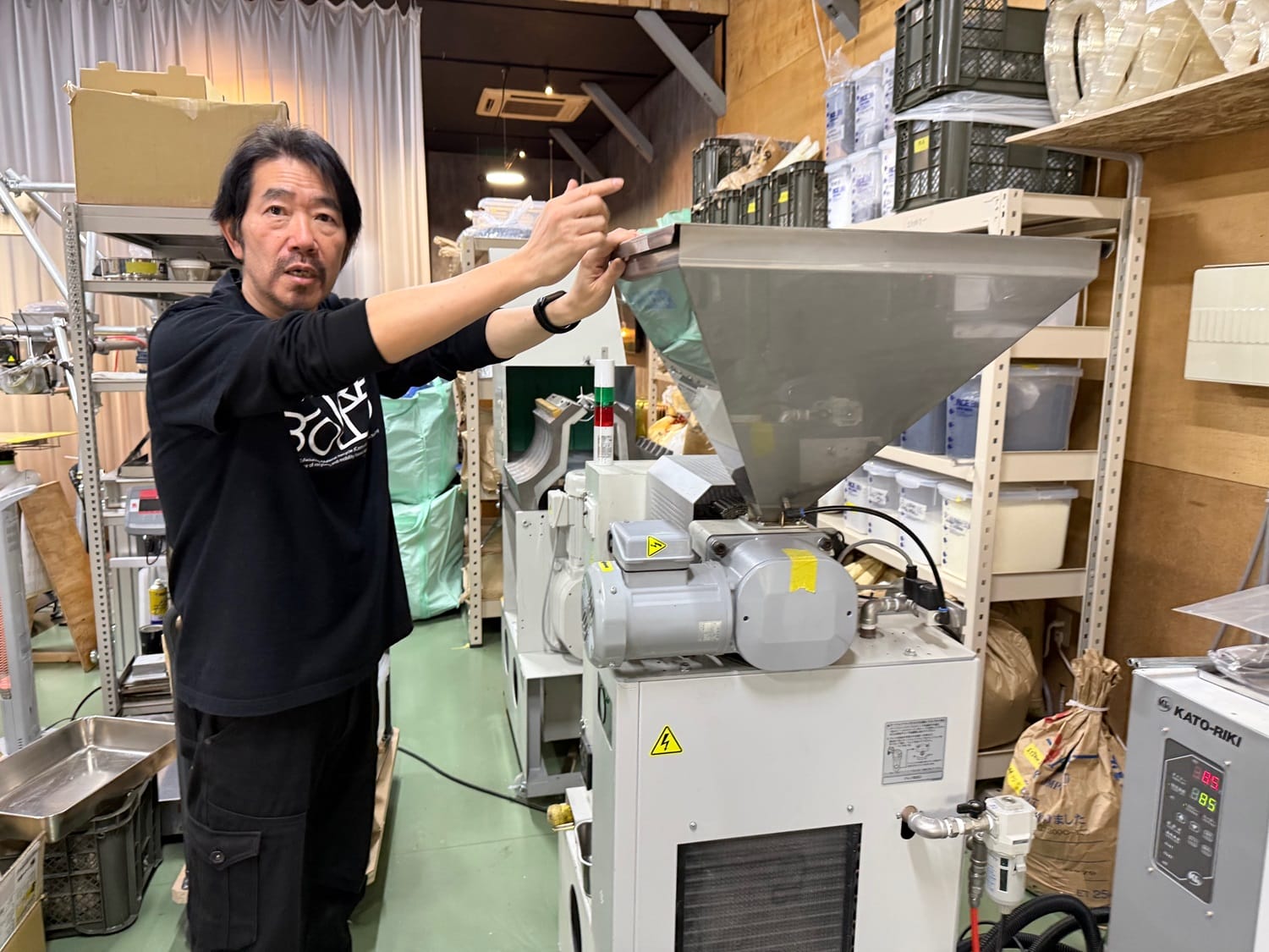 ペレットをつくる機械を前に、工房を説明する原さん